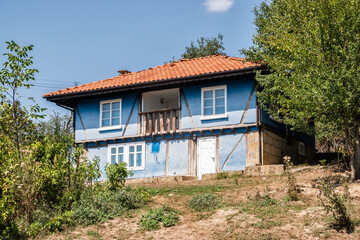 Old blue painted rural house on hillside of Balkan village closeup on sunny summer day