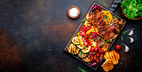 Grill it!. Grilled chicken, vegetables, mushrooms and toast on oak serving board. Brown background, top view
