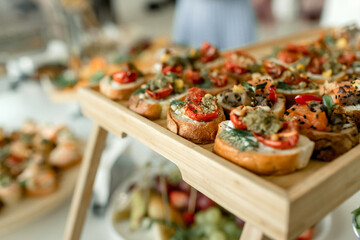 Delectable array of gourmet canapes beautifully displayed on a wooden tray at a vibrant social gathering
