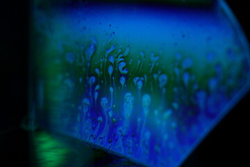 Bright reflection of liquid in macro, blue and silver colors, rainbow background, Blue bubbles in...