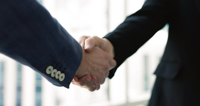 Close up view of two unknown businessmen in suits finishing negotiations with handshake. Gesture signifying finalization of successful agreement or partnership, business etiquette, cooperation, trust