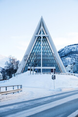 Arctic Cathedral in Tromso, Norway in winter. Tromsdalen Church with unusual modernist architecture and glass facade in snowy landscape. Vertical orientation