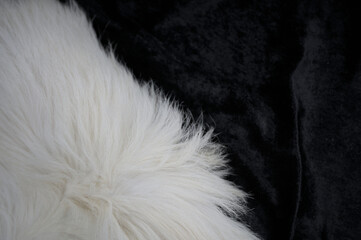 Flauschiges weißes Fell auf schwarzem Stoff unten links