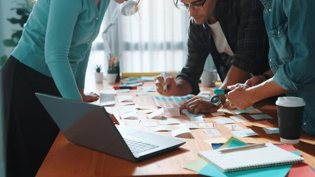 Skilled business team looking at laptop and pointing logo design while making decision to choosing main theme color and planning marketing campaign. Smart start up group working together. Symposium.