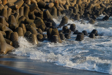 Waves crashing against the concrete breakwater. Wave breakers to prevent beach erosion due to...