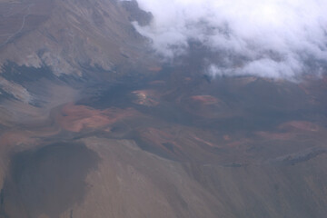 Aerial view of rugged mountain terrain with clouds and rocky landscapes during a cloudy day
