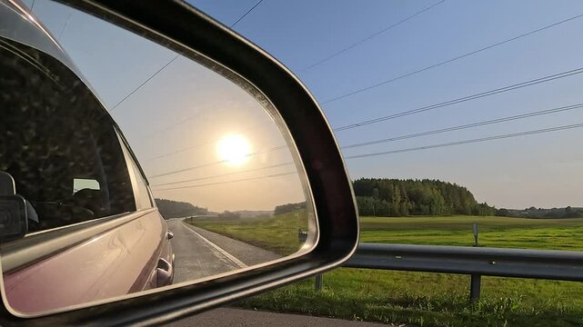 Red automobile in motion. View in the rear view side mirror of a auto, driving a red car along the track