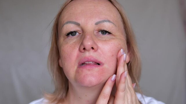 Portrait the fingers holding the flabbiness adipose sagging skin, Flabby skin and loose, swelling and ptosis beside the eyelid, dark spots and wrinkle on the face, health care and beauty concept.