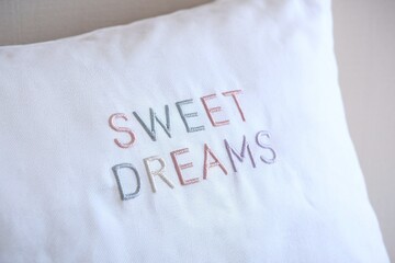 White pillow with embroidered 'Sweet Dreams' text in pastel colors