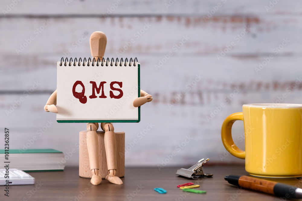 Poster there is notebook with the word qms. it is an abbreviation for quality management system as eye-catc