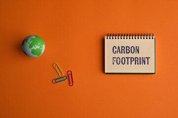 There is notebook with the word Carbon Footprint. It is as an eye-catching image.