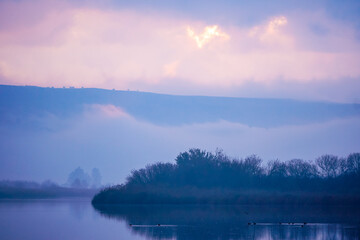 Serene Sunrise Over Misty Lake and Hills