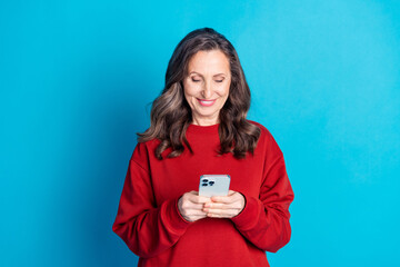 Portrait of nice aged woman use phone wear red sweater isolated on blue color background