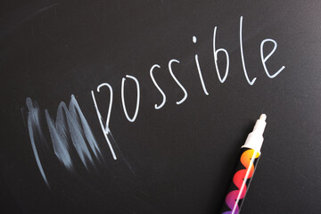 on a black chalk board the inscription impossible with the prefix erased, motivation for success, away with doubts