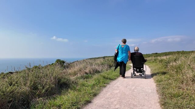 Devon England UK. 30.09.2024. Video. Elderly man using an electric wheelchair along a coastal pth in south Devon UK.
