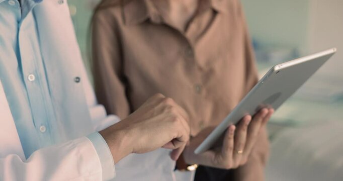 Close up male doctor showing x-ray images, health test results to female patient at her visit in clinic, explaining treatment plan and options, provide professional medical care using modern device