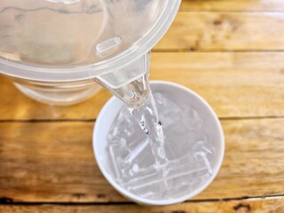 Pouring water and ice in a glass