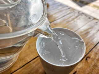 Pouring water and ice in a glass