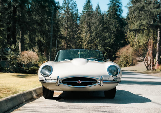 Jaguar E-type 4.2 Coupe parked on street with natura background. Vintage car front view. British sports car produced from 1961 and 1974. Selective focus. Vancouver, Canada March 2023