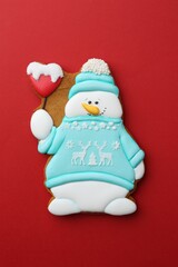 Tasty Christmas cookie in shape of snowman on red background, top view