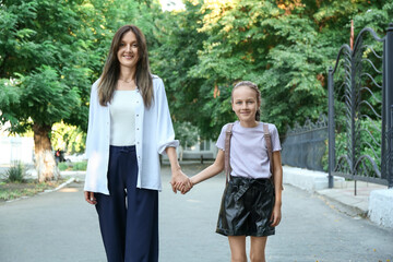 Happy mother and daughter holding hands outdoors