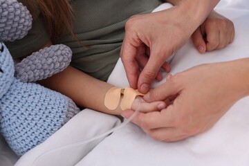 Doctor examining little girl on bed at hospital, closeup