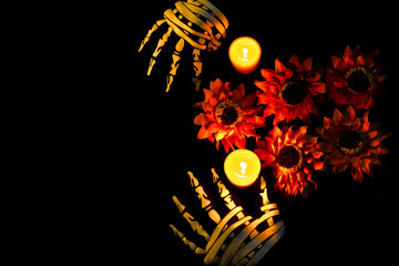 All Souls' Day: bony hands adorning altar with flowers and candles on black background