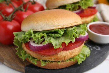 Delicious vegetarian burgers with chickpea cutlets, tomatoes and sauce on white table, closeup