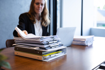 Businesswoman Organizing a Stack of Reports and Documents in a Modern Office Environment