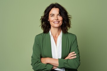 Portrait of smiling businesswoman with crossed arms standing against green background