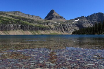 Hidden Lake at the base of some glacial mountains clear blue water with colorful rocks 