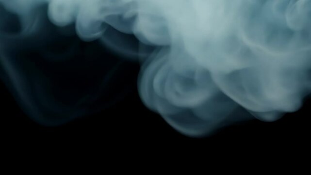 Wisps of smoke swirl and intertwine against a black background, creating soft ethereal patterns in the air. The delicate motion gives a sense of mystery and calm.