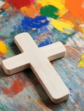 A simple wooden cross sits on a colorful background perfect for Vacation Bible School crafts.  This image represents faith, hope, and love.