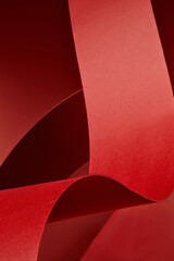 An enclosed view of a red paper strip that is bent. A shape is formed by folding and twisting the...