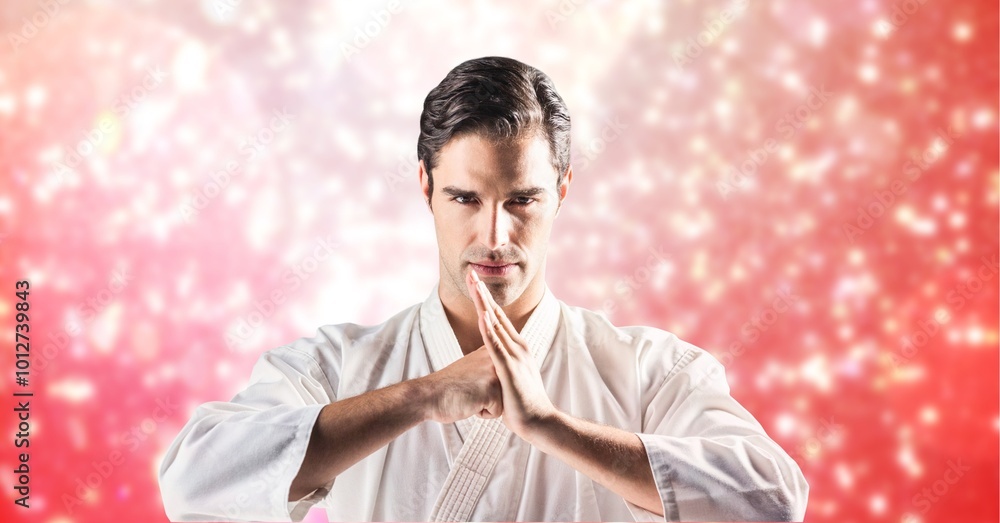 Canvas Prints Caucasian male martial artist performing hand salute against spots of light on red background