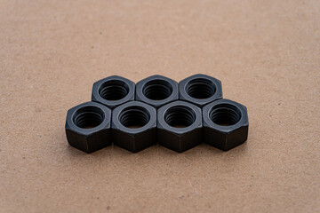 A group of black hex nuts arranged in a neat pattern. These versatile fasteners are essential for various construction and mechanical projects.