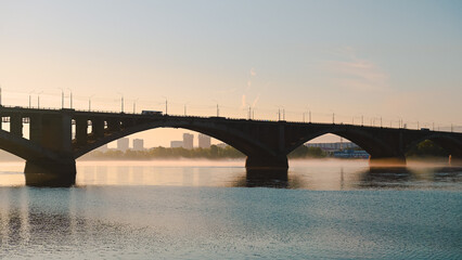 the bus goes over the bridge in Krasnoyarsk at dawn