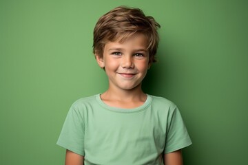 Portrait of a cute little boy with blond hair on a green background