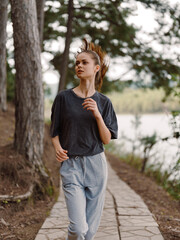 Young athletic woman jogging along a scenic path near a river, dressed in casual sportswear, enjoying a healthy lifestyle in nature Fitness and wellness concept