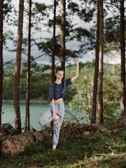 Graceful young woman practicing yoga in a tranquil forest setting, surrounded by trees and a serene lake in the background Wellness and nature concept