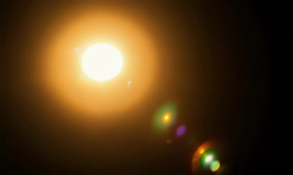 A large  bright moon in the night sky  with lens flares.