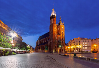Obraz premium St. Mary's Basilica in Krakow, Poland, before dawn in the Main Market Square. The illuminated twin towers are visible along with surrounding historic buildings