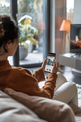 Person sitting on a couch, intently adjusting home security cameras through smartphone app interface