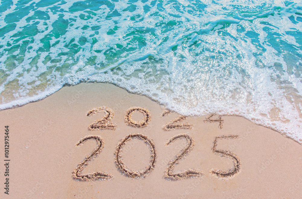 Wall mural message year 2024 replaced by 2025 text written on beach sand background. good bye 2024 - 2025 happy