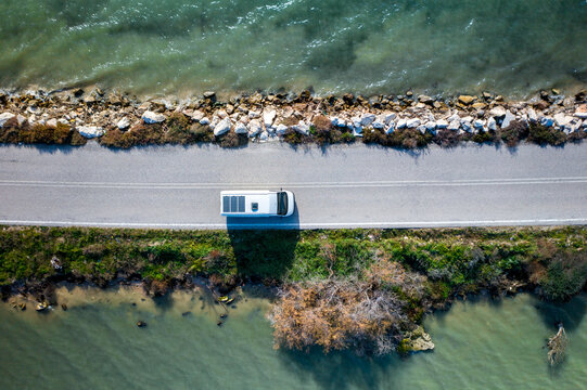 Drone top view of a camper van on a road between two lakes