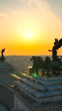 Vista aerea dell'angelo con i cavalli in cima all'altare della Patria nel centro della citt&agrave; di Roma. Il sole in controluce passa attraverso le ali.