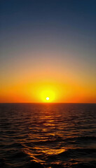 A peaceful sunset over the sea with warm golden hues reflecting on the water, creating a tranquil atmosphere perfect for relaxation and beachside retreats.