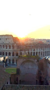 Il colosseo illuminato dal sole alle prime luci dell'alba. Roma, Italia.
Vista erea del colosseo con i raggi del sole che attraversano gli archi. Video Verticale. 

