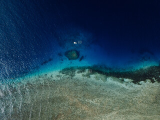 Seascape aerial drone view over reef with boats in Bali