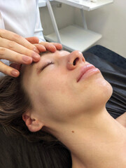 Naklejka premium Spa facial massage. A young European girl gets a face, neck and head massage. Cosmetic care, face washing.